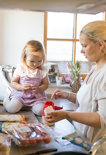 Mutter und Kleinkind in der Küche, Kind sitzt auf Arbeitsplatte